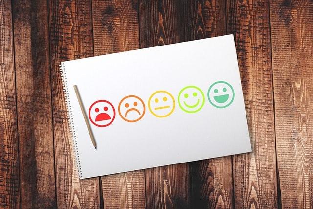 A notebook page with colored smiley faces ranging from sad to happy, symbolizing a satisfaction scale.