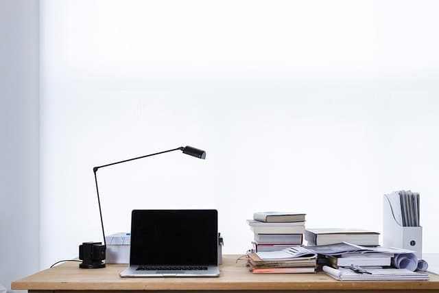 A computer and notebooks on the desk.