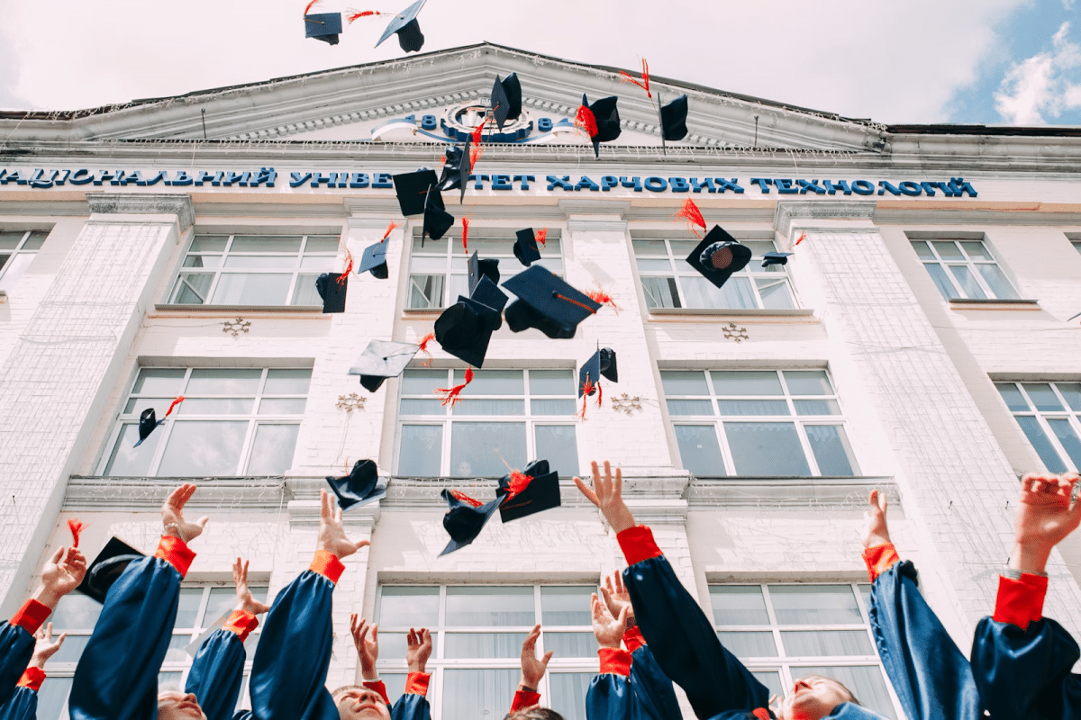 Studenci świętujący zakończenie studiów, rzucając czapki.